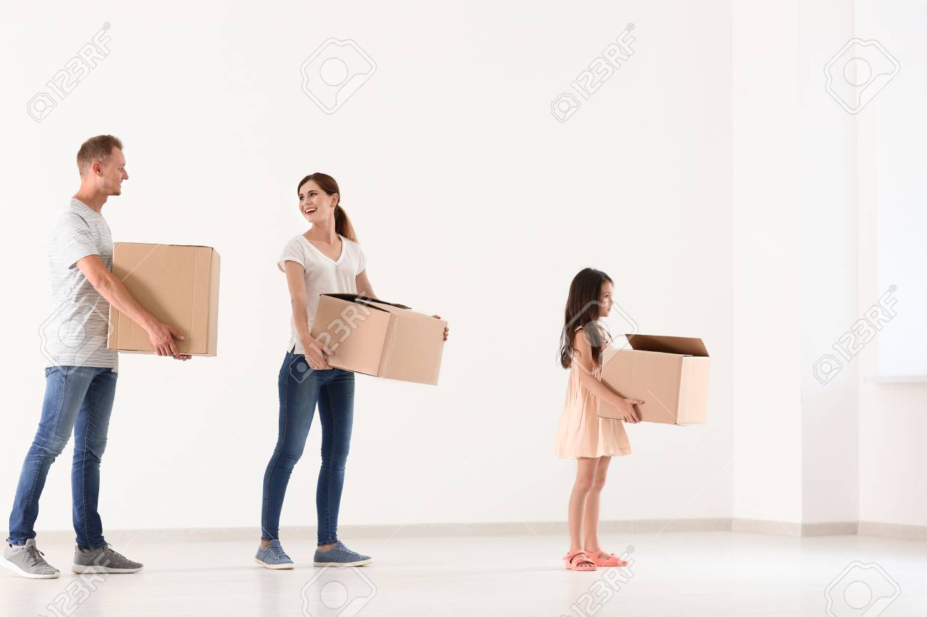 Happy family with cardboard boxes after moving into new house indoors